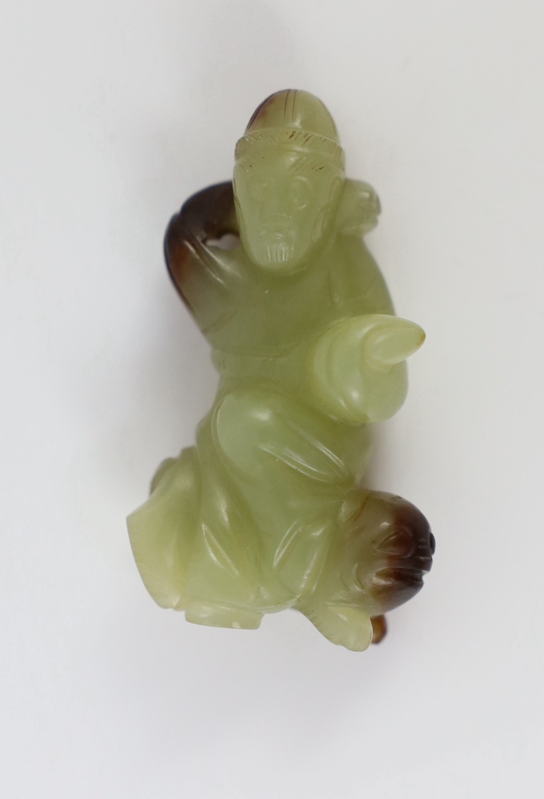 A Chinese yellow and brown jade figure of a man seated on a creature, 19th century, 4.3cm high